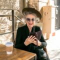 elderly woman in black holding black smartphone