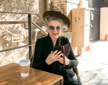 elderly woman in black holding black smartphone