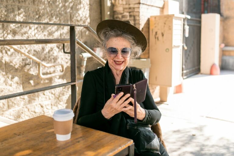 elderly woman in black holding black smartphone